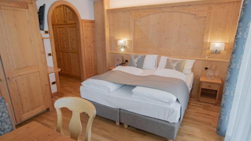 a bedroom with a large bed and a chair at Hotel Diamant Park in Campitello di Fassa