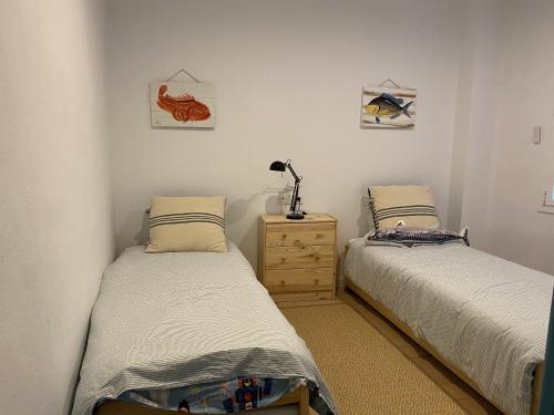 a bedroom with two beds and a dresser at Can Nicasi in L'Escala