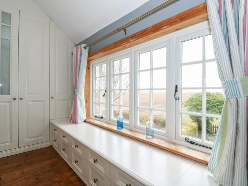 Cette chambre dispose d'une grande fenêtre et de placards blancs. dans l'établissement Grange Farm Cottage, à Sutton Bridge