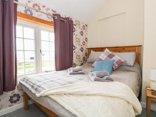 a bed with towels on it in a room with a window at Grange Farm Cottage in Sutton Bridge
