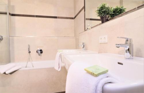 a bathroom with two sinks and a bath tub at Alpin & See Resort - Pinzgau Holidays in Zell am See