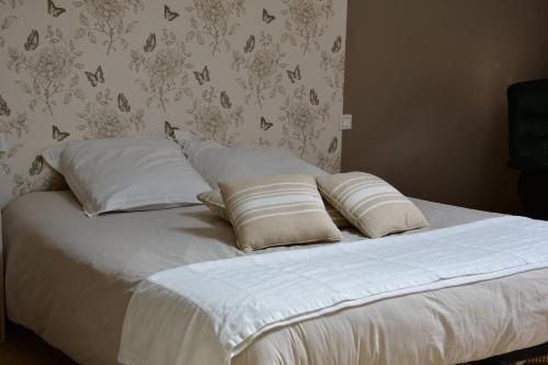 - un lit avec des draps et des oreillers blancs dans une chambre dans l'établissement Le Relais de Chavagné, à Chauray