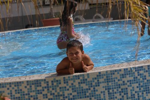 a boy in a swimming pool with a girl in the background at Grand Hotel Paradiso in Catanzaro Lido