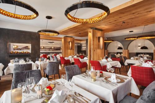 a restaurant with white tables and red chairs at Hotel Alpenhof in Bad Wiessee