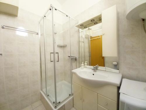 een badkamer met een glazen douche en een wastafel bij Apartment Karlo in Medulin