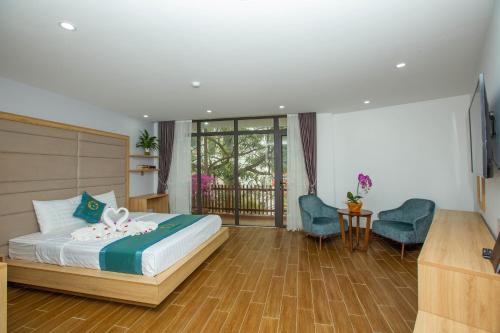 sypialnia z łóżkiem, telewizorem i krzesłem w obiekcie Emerald Hotel Cát Bà w mieście Cát Bà