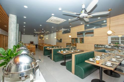 een restaurant met groene stoelen en tafels en een plafondventilator bij Emerald Hotel Cát Bà in Cat Ba