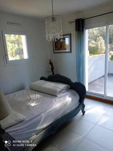 Ce lit se trouve dans une chambre dotée d'une fenêtre et d'un lustre. dans l'établissement Maison charmante à La Tranche-sur-Mer avec jardin clos, à La Tranche-sur-Mer