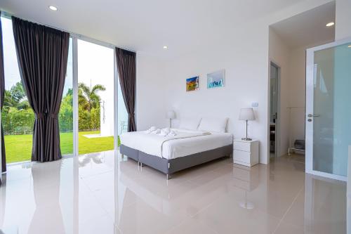 a white bedroom with a bed and a large window at Modern 3 Bedroom Private Pool Villa PMK-A1 in Khao Tao