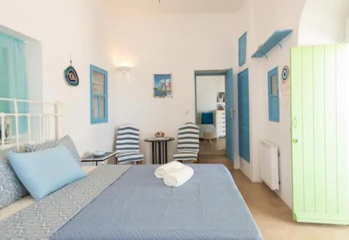 a bedroom with a blue bed and a room with chairs at Casa Annaise Mykonos - Cycladic House with Jacuzzi in Mýkonos City