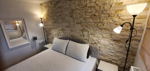 a bedroom with a bed with a stone wall at Cosy House Studio & Parking in Kaunas