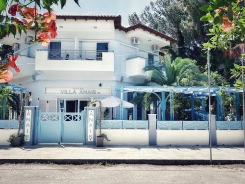 een wit gebouw met blauwe poorten ervoor bij Hotel Villa Anais in Prinos