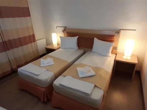 two beds in a small room with two lamps at Pensiunea Energy in Căpuşu Mic