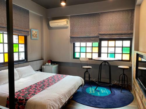 een slaapkamer met een bed, een tafel en 2 krukken bij Cun Cuisine Homestay in Tainan