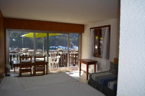a bedroom with a bed and a table and a balcony at Village vacances Le Savoy in Le Grand-Bornand