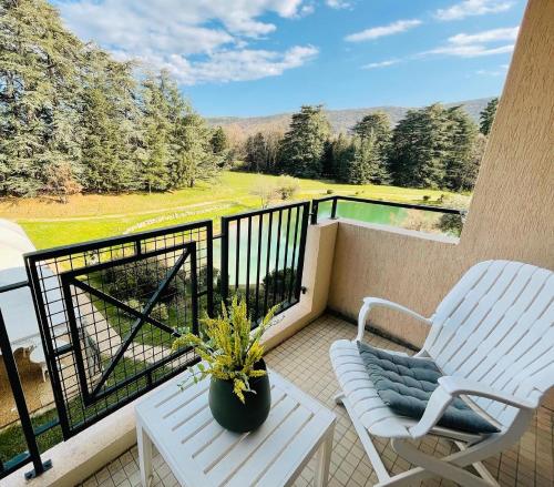 a balcony with a white chair and a table and a chair at Domaine Les Sources de Dieulefit in Dieulefit