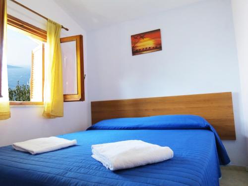 a bedroom with a bed with blue sheets and a window at Baia Serena in Vico Equense