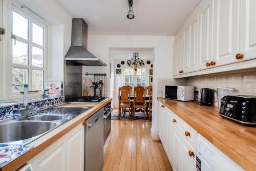 a kitchen with white cabinets and a sink at Cosy Victorian Terrace house in Jericho in Oxford