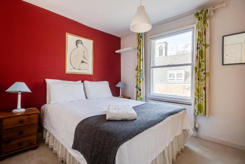 um quarto com uma cama com uma parede vermelha em Characterful & Cosy Jericho House (sleeps up to 8) em Oxford