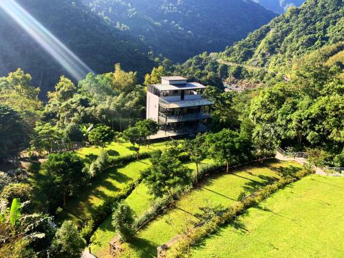 a building in the middle of a field with trees at Sla Ulay Backpacker Hostel in Wulai