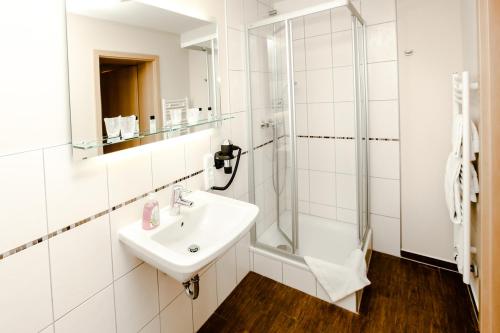 y baño blanco con lavabo y ducha. en Hotel Krone, en Monheim