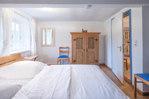 ein Schlafzimmer mit einem großen weißen Bett und einem Stuhl in der Unterkunft Reetdachhaus zur Sandkuhle in Ostenfeld