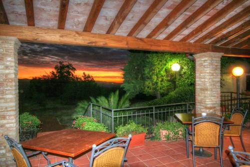 a patio with a table and chairs and a painting of a sunset at Hotel Residence Villa Rioddi in Volterra