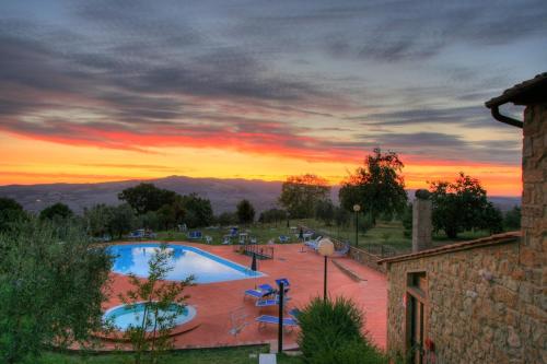 a view of a swimming pool at sunset at Hotel Residence Villa Rioddi in Volterra