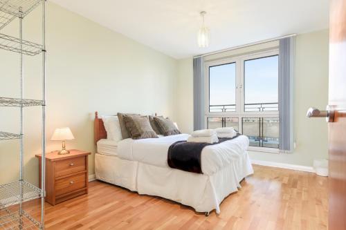 a white bedroom with a large bed and a window at Britannia Penthouse in Edinburgh