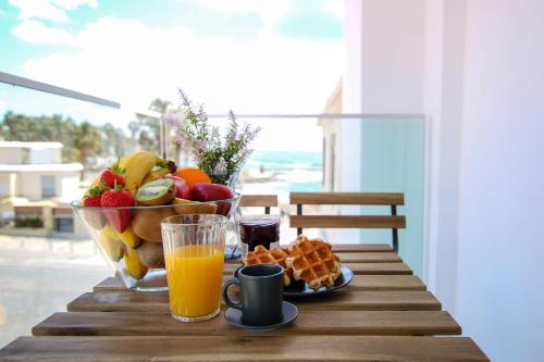 a table with a bowl of fruit and a glass of orange juice at Phaedrus Living Seaside Luxury Flat Athina 108 in Paphos
