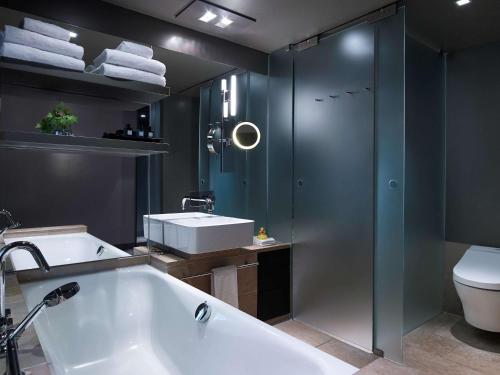 a bathroom with a tub and a sink and a toilet at Sofitel Munich Bayerpost in Munich