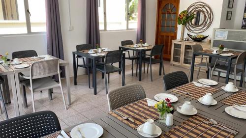 a dining room with tables and chairs in a room at Hotel Plein Soleil in Grand Anse