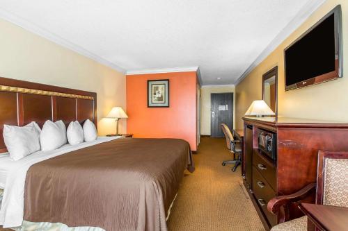a hotel room with a bed and a flat screen tv at Quality Inn & Suites Bell Gardens-Los Angeles in Bell Gardens