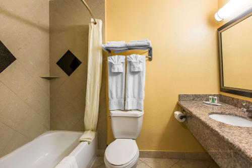 a bathroom with a toilet and a sink and a tub at Quality Inn & Suites Bell Gardens-Los Angeles in Bell Gardens
