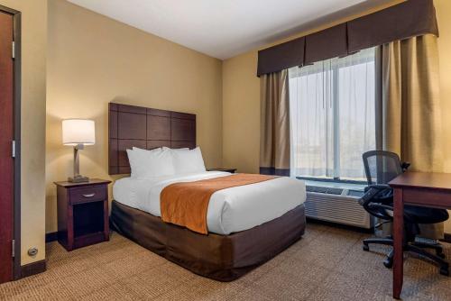 a hotel room with a bed and a desk and window at Comfort Suites Airport South in Montgomery