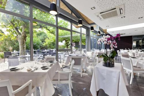 a restaurant with white tables and chairs and windows at Hostellerie Saint Germain in Saint-Germain-lès-Arlay