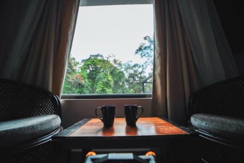 two cups on a table in front of a window at VANYA by Citrine in Nelliyampathy