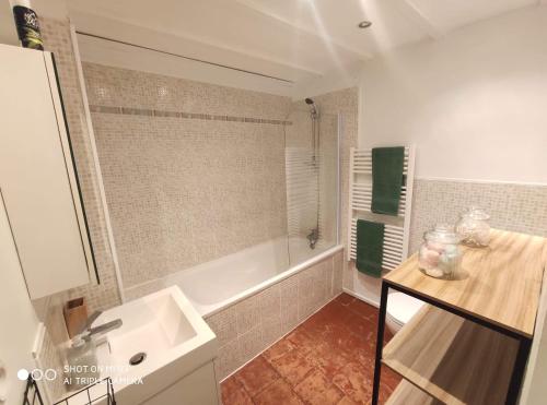 La salle de bains est pourvue d'une baignoire blanche, d'un lavabo et d'un lavabo. dans l'établissement La petite maison dans la bastide, à Carcassonne
