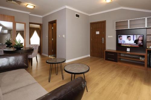 a living room with a couch and a tv at New Balturk Hotel Izmit in Kocaeli