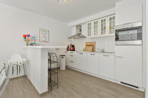 a white kitchen with white cabinets and a counter at Ruim app met 3 slpks en 2 badkamers vlakbij de zee in Knokke-Heist