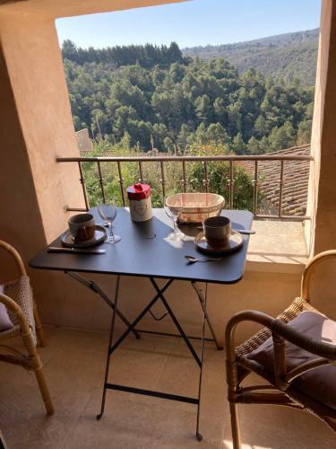 - une table avec des verres à vin sur un balcon avec vue dans l'établissement Rose, à Bonnieux