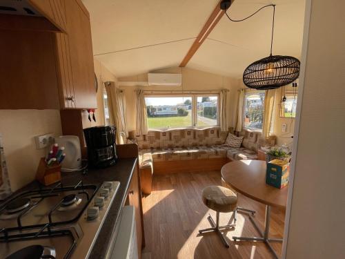 eine Küche und ein Wohnzimmer mit einem Herd und einem Tisch in der Unterkunft Duindoorn 46 in IJmuiden