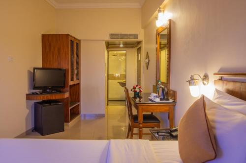 a bedroom with a bed and a desk and a television at Nanutel Margao in Madgaon