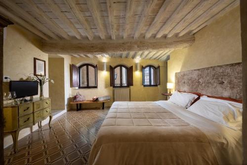 a bedroom with a large bed and a television at Il Battistero Siena Residenza d'Epoca in Siena