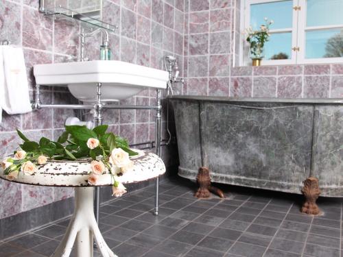 a bathroom with a sink and a table with flowers on it at Dufweholms Herrgård in Katrineholm