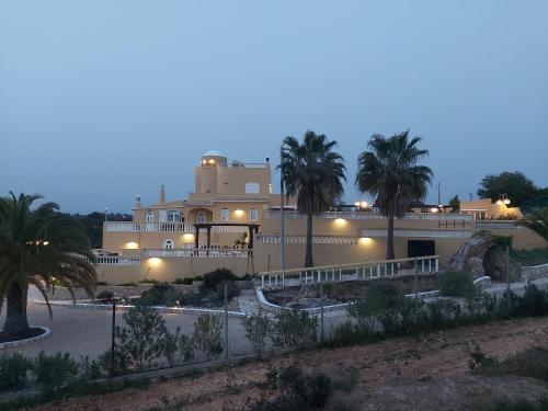 
a large white building with palm trees at Quinta Nova Vale Del Rey in Carvoeiro
