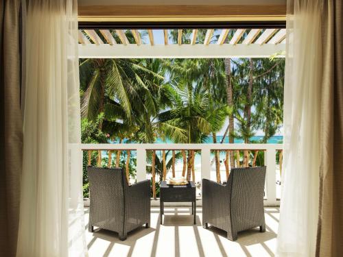a room with a porch with chairs and palm trees at Villa Caemilla Beach Boutique Hotel in Boracay