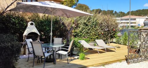 eine Terrasse mit einem Tisch, Stühlen und einem Sonnenschirm in der Unterkunft STUDIO VILLA NUI in Cuers