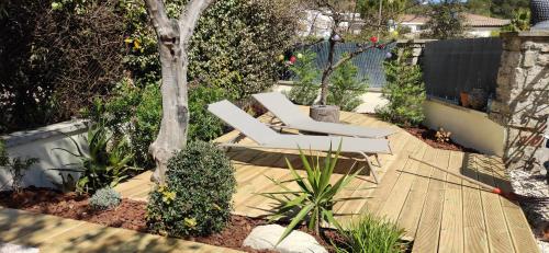 eine Terrasse mit zwei weißen Stühlen und einem Baum in der Unterkunft STUDIO VILLA NUI in Cuers