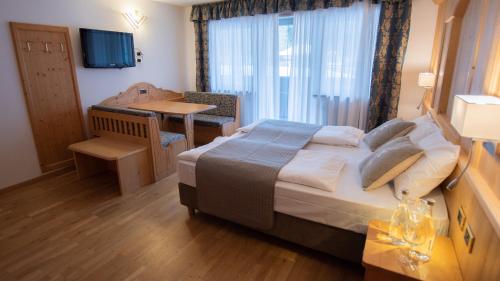 a bedroom with a bed and a table and a window at Hotel Diamant Park in Campitello di Fassa